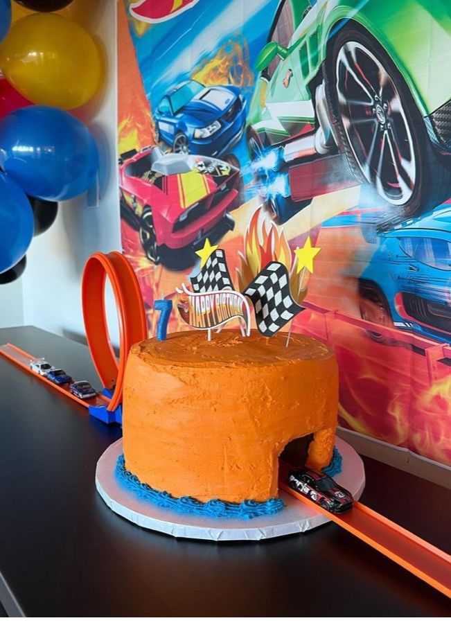 a birthday cake sitting on top of a table next to some balloons and streamers