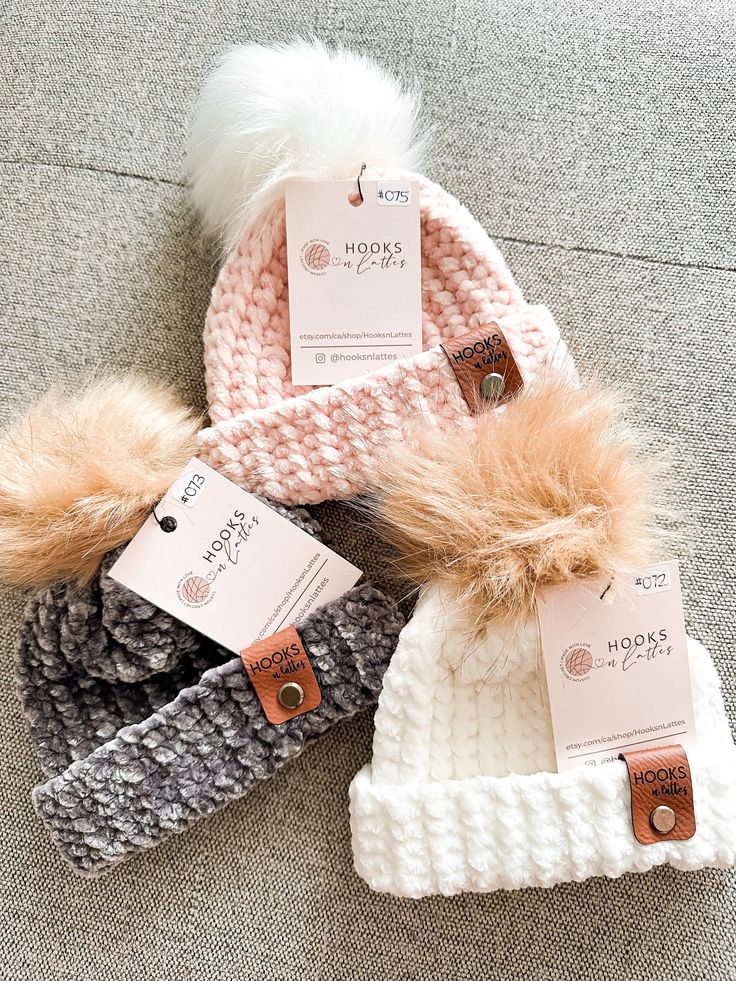 three hats with fur pom - poms are on the floor next to each other