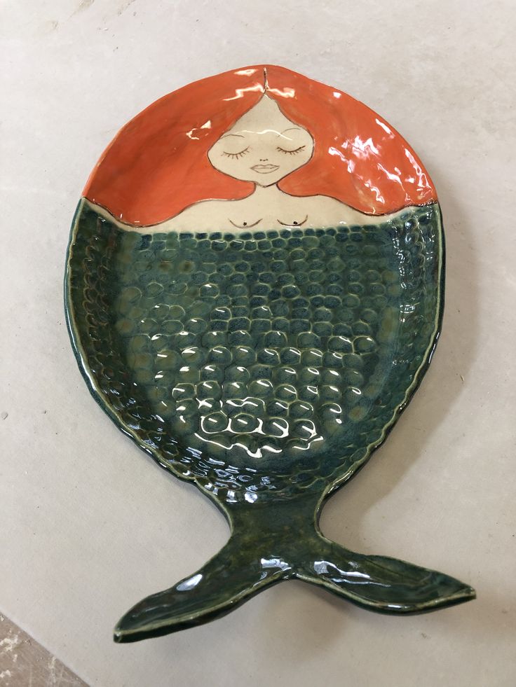 a ceramic plate with a mermaid design on it