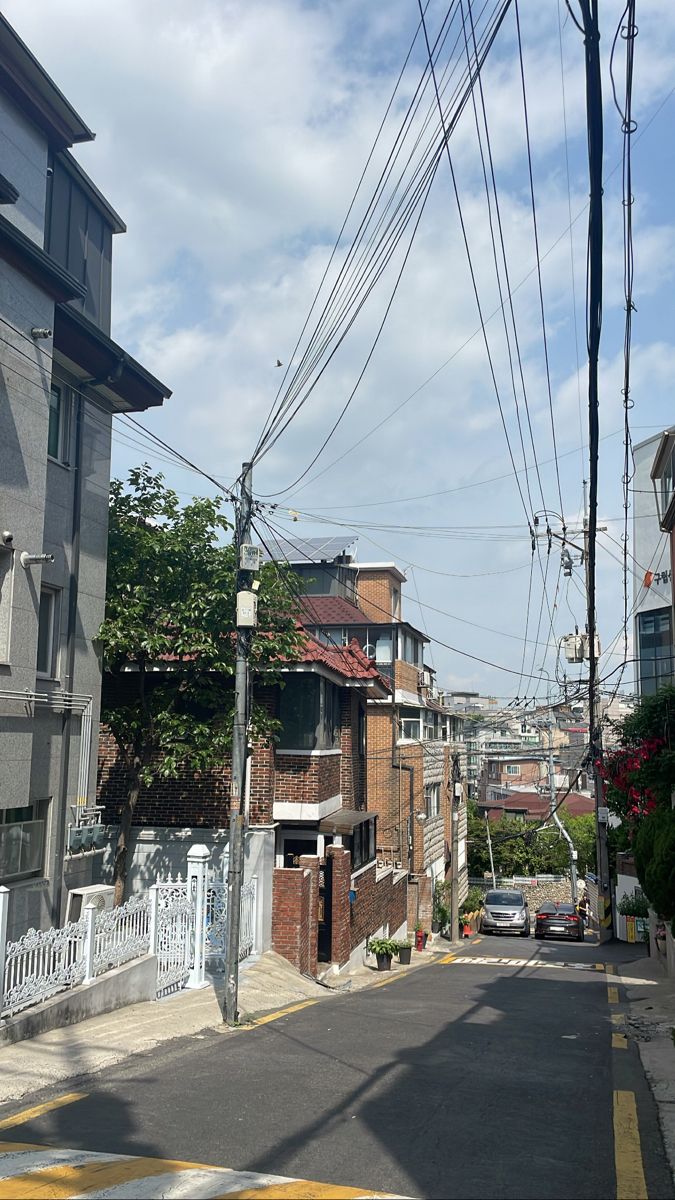 an empty street with power lines above it and houses on the other side in the distance