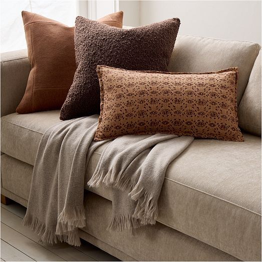 three pillows are sitting on a couch in front of a window