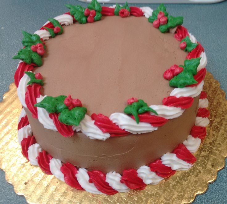 a chocolate cake decorated with red, white and green icing on a gold plate