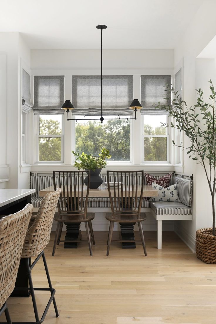 a dining room table with four chairs and a plant in the center is surrounded by wicker stools