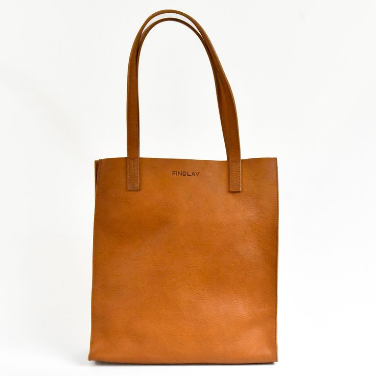 Tall market tote crafted in pebbled vegetable tanned leather and an unlined interior. The sleek minimal design makes it a great everyday bag for work, school or a visit to the farmers market. It features reinforced bottom support and large interior pocket to keep your keys and phone close by. - Pebbled Full Grain Italian Vegetable-Tanned leather - Unlined Interior - Includes 1 large interior pocket - Reinforced bottom support - Ethically Handcrafted in the Dominican Republic Modern Everyday Bag With Smooth Grain, Modern Everyday Shoulder Bag In Vegetable Tanned Leather, Classic Everyday Bag In Vegetable Tanned Leather, Classic Vegetable Tanned Leather Bags For Everyday, Classic Everyday Shoulder Bag In Vegetable Tanned Leather, Everyday Vegetable Tanned Leather Shoulder Bag With Double Handle, Classic Vegetable Tanned Leather Shoulder Bag For Everyday, Everyday Double Handle Vegetable Tanned Leather Shoulder Bag, Classic Vegetable Tanned Leather Shoulder Bag For Shopping