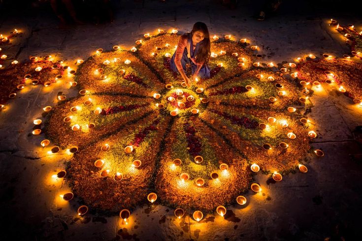 a woman sitting in the middle of a circle of candles