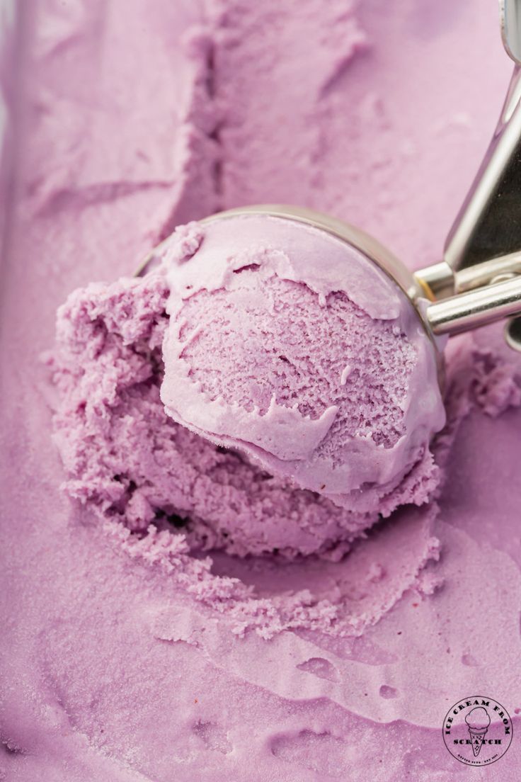 a scoop of pink ice cream in a metal container with a spoon on the side