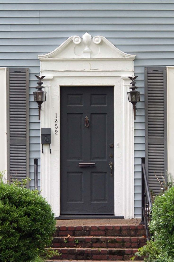 the front door of a house with two lamps on either side and steps leading up to it