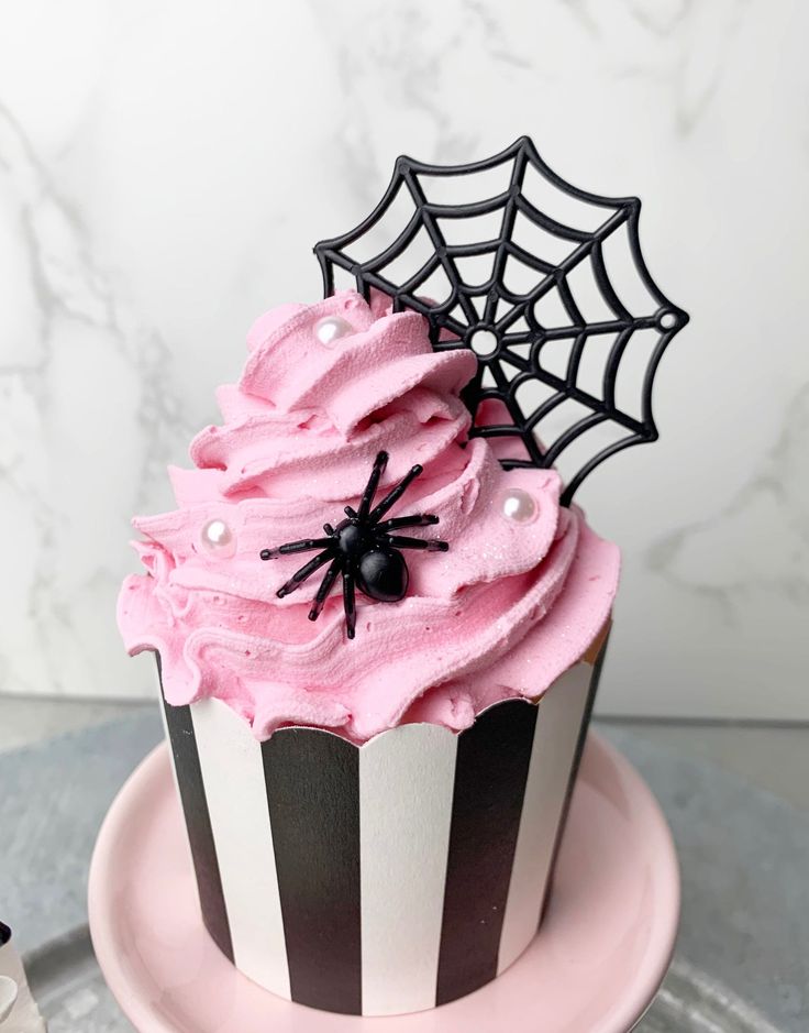 a cupcake with pink frosting and spider web decoration