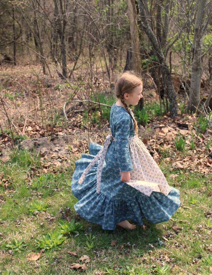 Four-piece ensemble!  Handmade dress is constructed from pre-washed new cotton floral/heart print fabric in muted teal and warm beige. Late 1800s historical costume for dress-up or reenactments! Princess seams and lots of ruffles for spinning! Eleven gold-tone 3/8" buttons, serged inner seams. Washable and dryable. From Butterick 4569 out-of-print pattern. For Girls Size 5 (24" chest, 21 1/2" waist) Actual chest: 26" Actual waist: 25 1/2" Length: 36 1/4" Apron is made from pre-washed new cotton fabric in complementary print, also washable and dryable. Adjustable back ties. Length: 20" Bonnet is made from new, pre-washed cotton in complementary muted teal and beige. Bonnet has a broad, stiffened brim and a skirt in the back to keep the sun off the wearer's face and neck. There are fabric ti Fall Dresses With Historical Design, Historical Design Fitted Cotton Dress, Long Sleeve Cotton Dresses With Historical Design, Long Sleeve Cotton Dress With Historical Design, Cotton Long Sleeve Dresses With Historical Design, Spring Victorian Costume Dress With Historical Design, Spring Victorian Dress Costume With Historical Design, Spring Victorian Dress Historical Design For Costume, Spring Victorian Dress With Historical Design For Costume