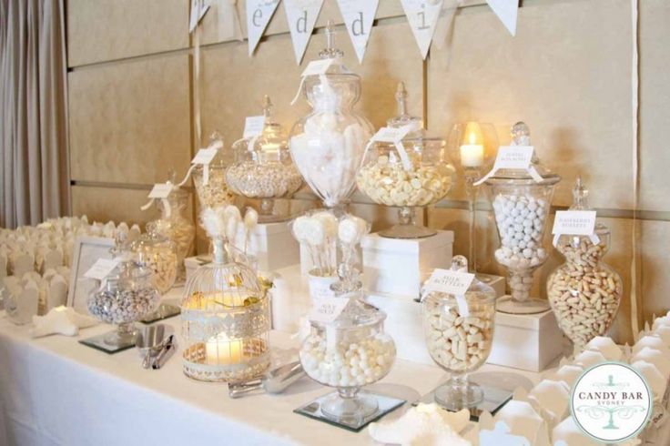 a table topped with lots of candy and candies on top of white cloth covered tables