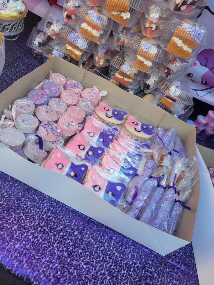 a box filled with lots of cupcakes on top of a purple table cloth