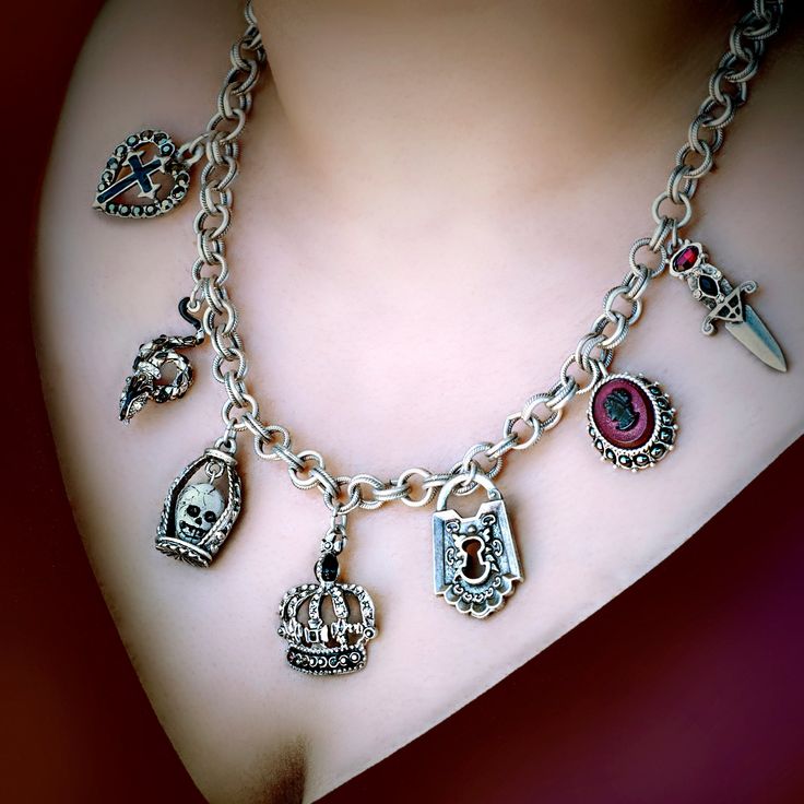 Yes, my darlings, you've won the dark lottery...It sold out at Viva Las Vegas. Now it's back in stock...Dark, sophisticated glamour. A chain of dimensional Loteria symbols are suspended from the vintage double rolo chain:Enameled Serpent Glass Skull, Gothic crown, Dungeon Padlock,Blood Red Cameo Cross of Darkness. Closes with a large rope ring and clasp with Elvira spider web tag. Hematite and crystal accents Created in our Los Angeles studio. 18" Long Objects of desire: the Elvira Jewelry Collection Elvira's many fans and admirers frequently ask for advice on how to give their own look a little edge. Her secret is jewelry. Now, everyone's favorite Vamp brings her special brand of magic to women worldwide, conjuring up mystery, seduction and glamour. Her collaborator is American designer a Fantasy Engraved Jewelry For Fantasy Events, Gothic Chain Jewelry As A Gift, Collectible Gothic Pendant Necklace, Gothic Collectible Pendant Necklace, Gothic Collectible Pendant Jewelry, Collectible Gothic Pendant Jewelry, Gothic Sterling Silver Necklace With Lobster Clasp, Gothic Sterling Silver Jewelry With Adjustable Chain, Victorian Sterling Silver Charm Jewelry