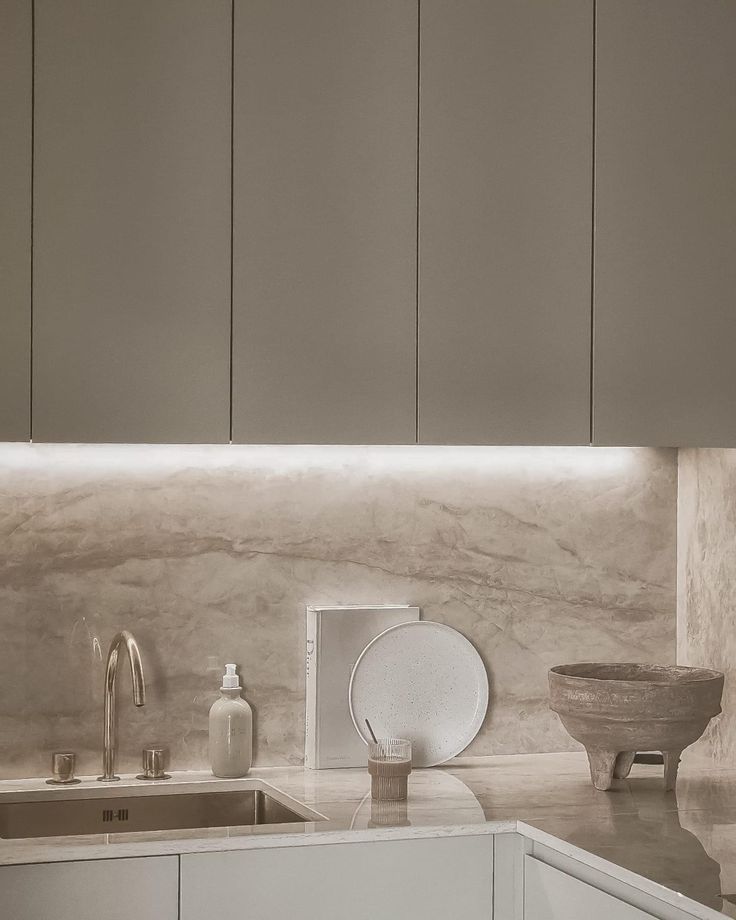 a kitchen with white cabinets and marble counter tops, along with a bowl on the sink