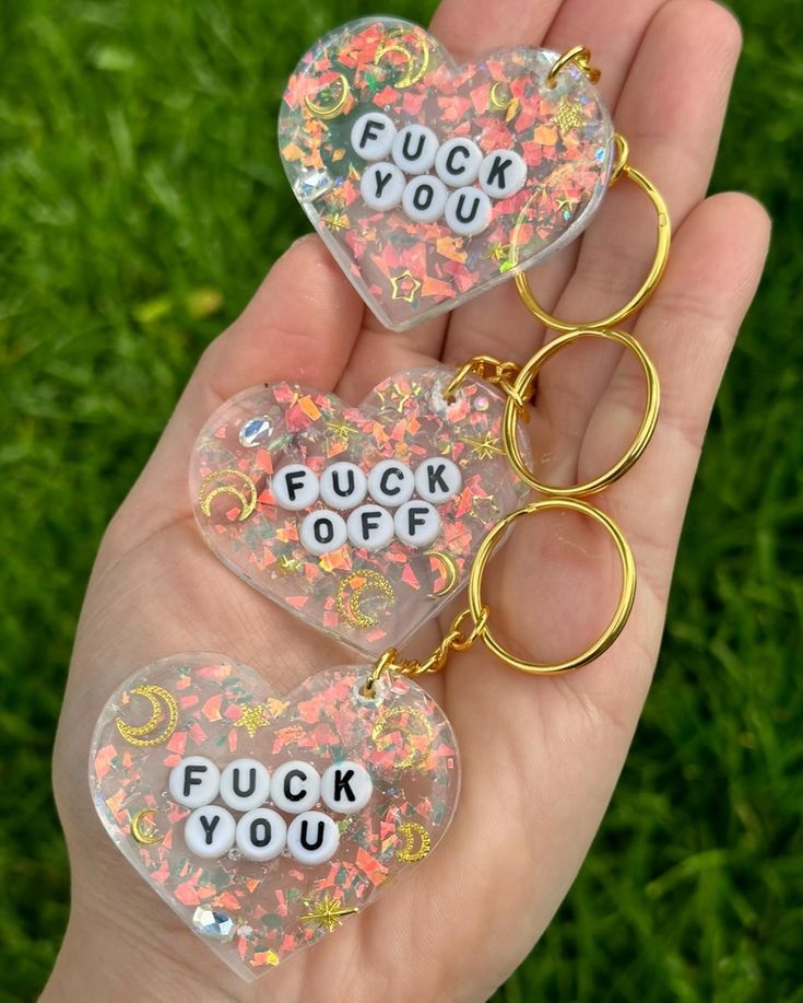 two clear heart shaped key chains with words on them that spell out f u k you