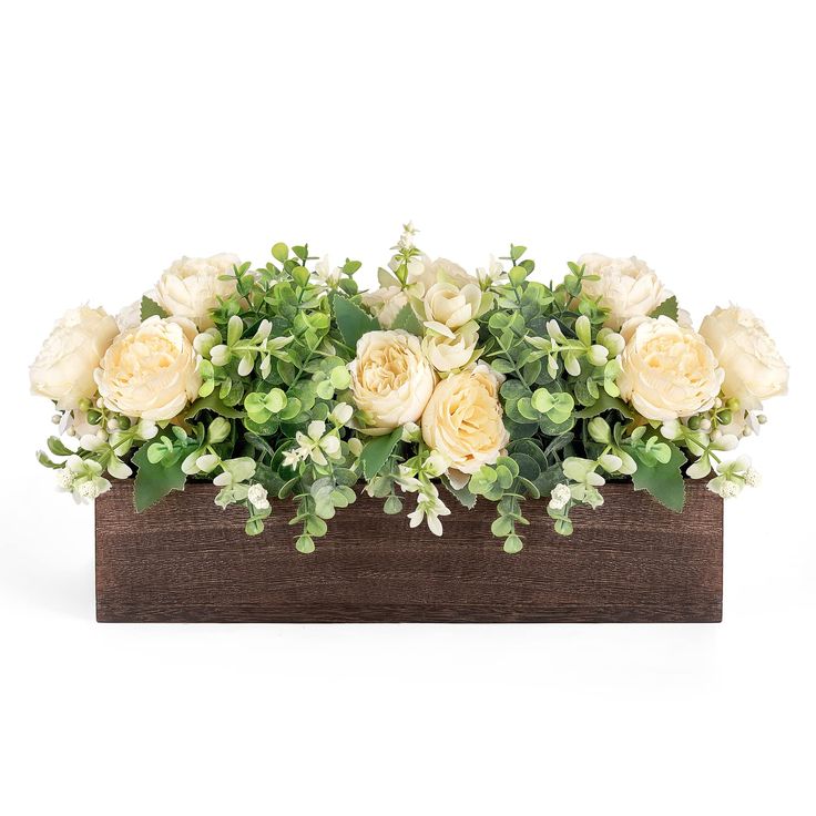 an arrangement of white and yellow flowers in a wooden box with greenery on the side