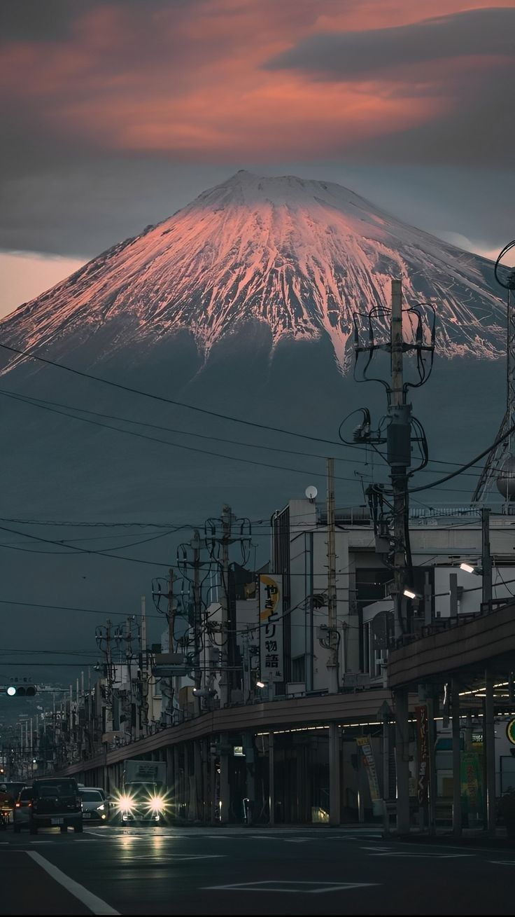 a very tall mountain towering over a city at night with cars driving down the street