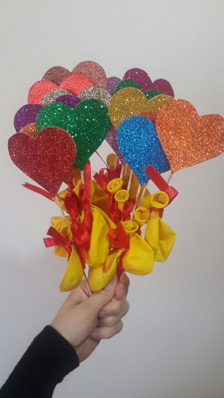 a hand holding a bunch of heart shaped lollipops