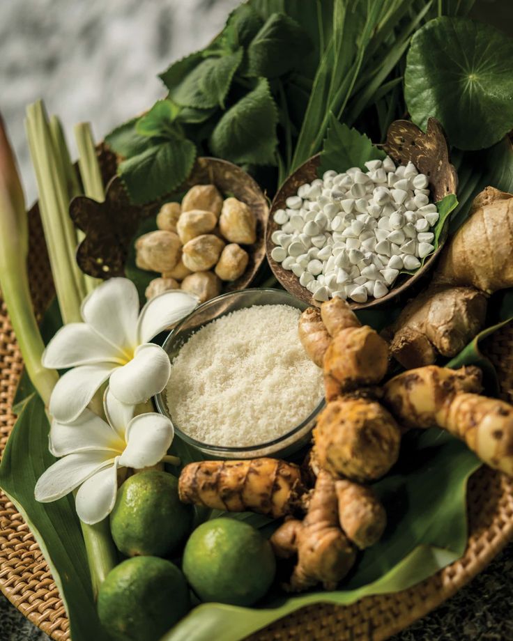 an assortment of ingredients are arranged on a plate with green leaves and white flowers in the center