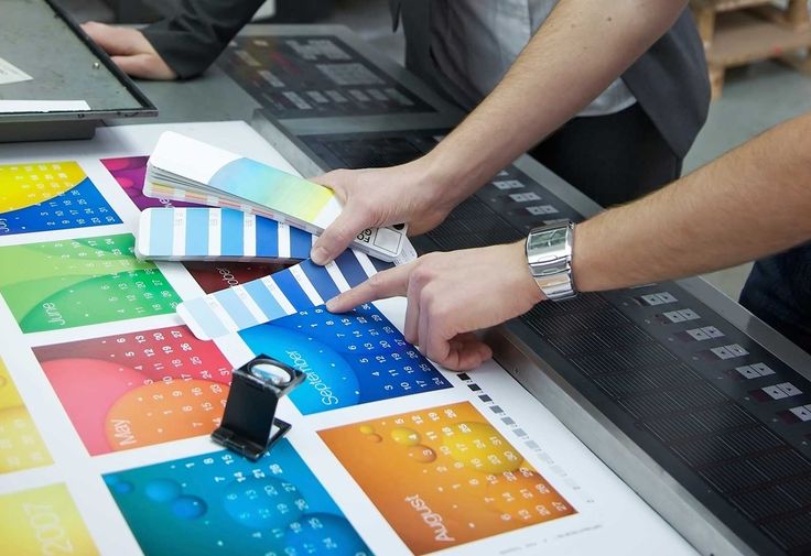 two people are working on an art project with color swatches and cell phones in front of them