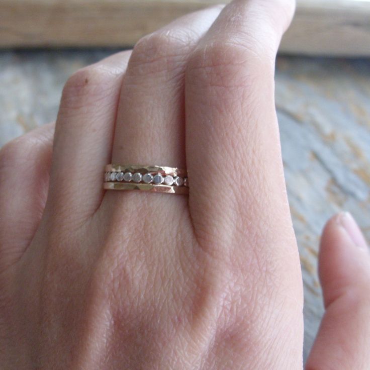 "Fashioned from sterling silver, the 1.5mm-wide \"tiny dots\" stacking band is antiqued to show detail, then tumbled for strength and a high polish. Two lightly hammered and highly polished 14k gold fill stacking bands complete the set. Each of the gold-fill bands is joined using plumb-gold solder (not brass), which has the highest possible gold content and allows for a seamless join. See brightsmith.etsy.com for these rings sold separately, or in a blackened silver finish as shown in the last p Dainty Hand Forged Gold Stackable Rings, Delicate Hammered Jewelry For Anniversary, Hand Forged Stackable Rings For Anniversary, Gold Hammered Stackable Rings For Anniversary, Adjustable Gold Stackable Rings With Rose Cut Diamonds, 14k Gold Hammered Stackable Rings For Anniversary, Dainty Hammered Stackable Wedding Rings, Stackable Double Band Jewelry For Anniversary, Stackable Toe Ring Jewelry For Anniversary