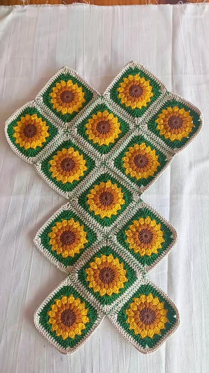 four crocheted sunflower coasters sitting on top of a white tablecloth