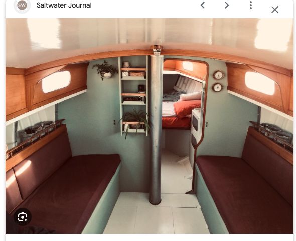 the inside of a small boat with two couches and shelves on either side of the room