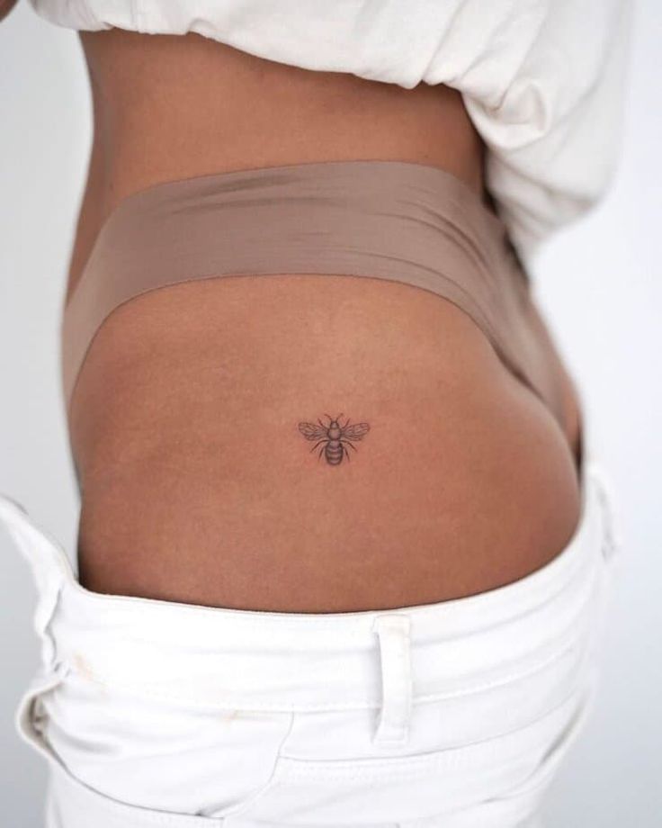 a woman's stomach with a small bee tattoo on her lower back and side