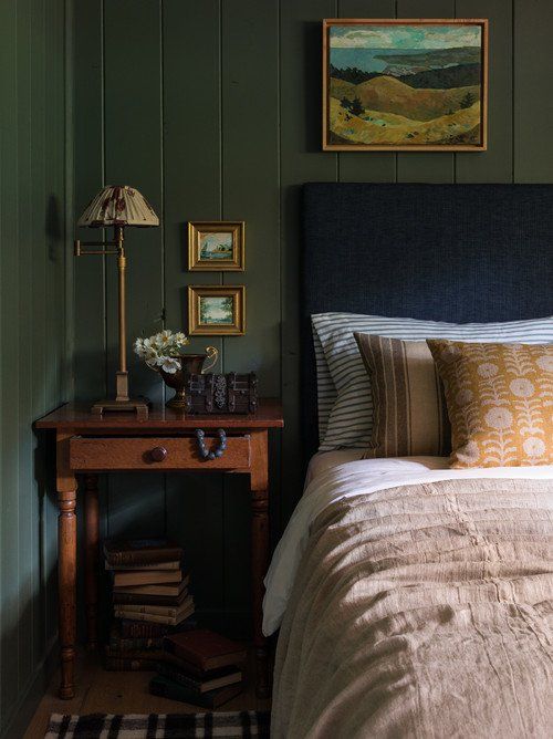 a bed sitting next to a wooden table with a lamp on it's side