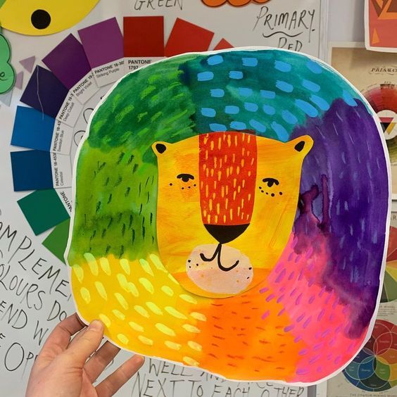 someone is holding up a paper plate with a colorful lion on it's face