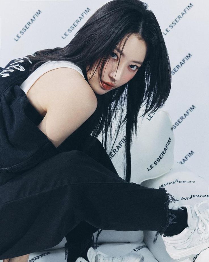 a young woman sitting on top of a white toilet wearing black pants and a t - shirt