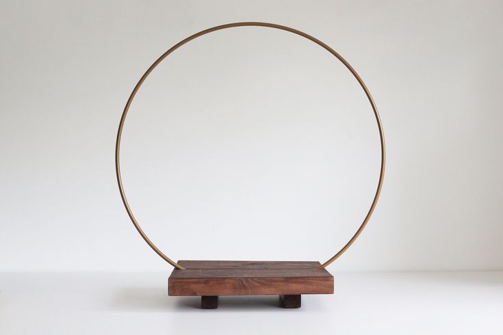 a wooden stand with a metal ring on it's end and a white wall in the background