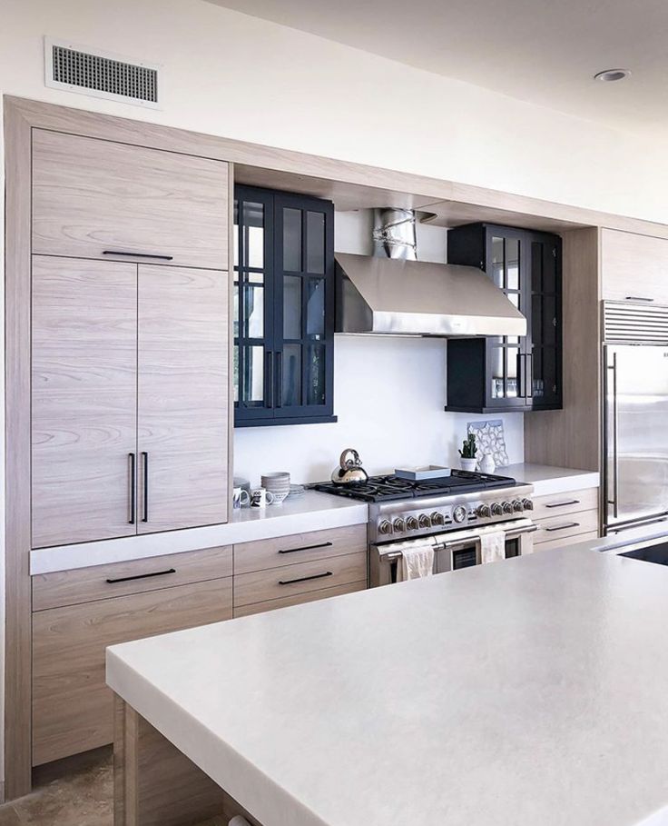 a kitchen with white counter tops and wooden cabinetry next to a stove top oven