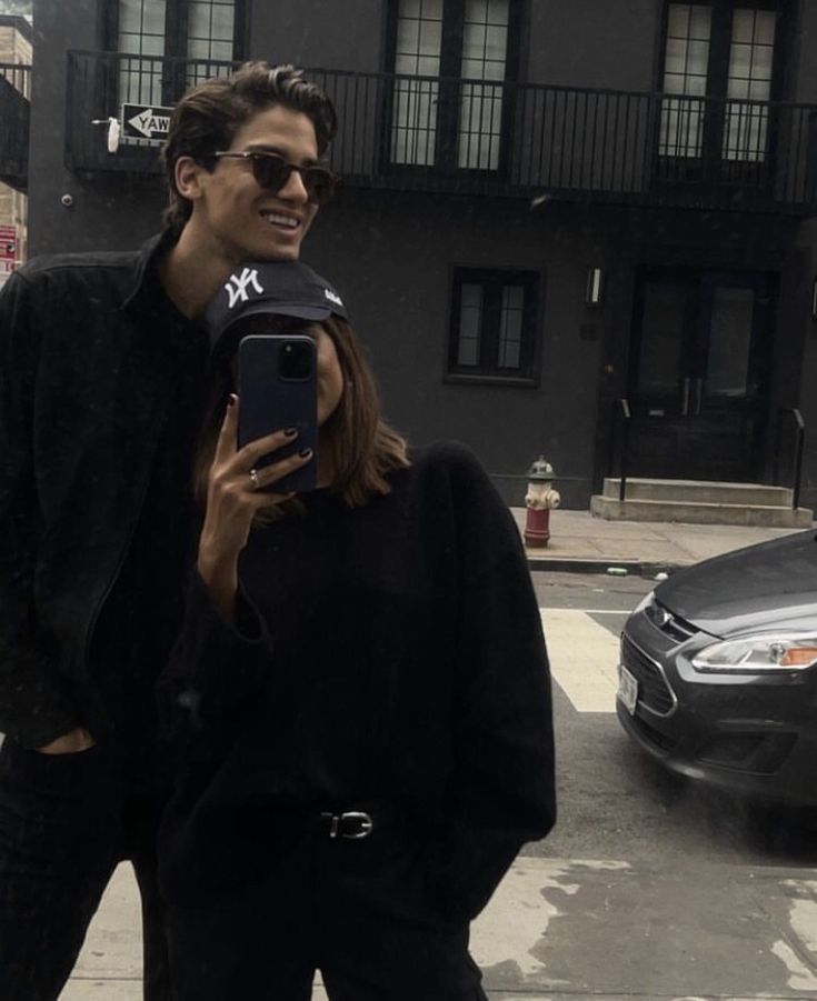 a man and woman standing on the street with their cell phones