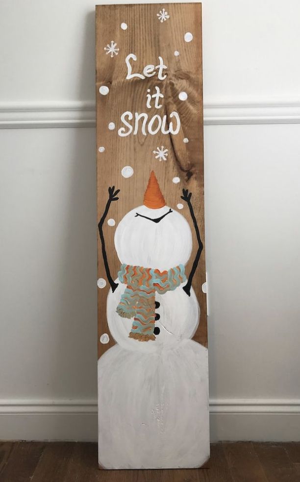 a wooden sign that says let it snow with a snowman wearing a hat and scarf