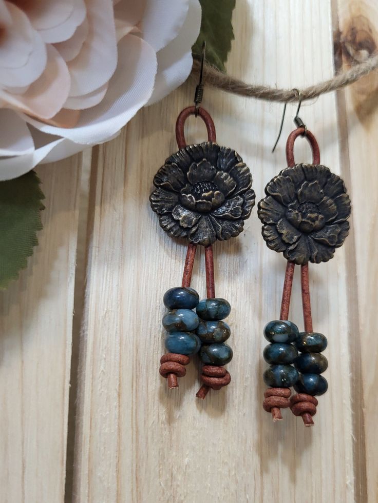 Bronze flower fashioned earrings on brown leather cord with teal dangle beads. Handmade Brown Bohemian Flower Earrings, Bohemian Bronze Earrings With Dangling Beads, Brown Copper Beaded Dangling Earrings, Brown Dangle Flower Earrings, Bohemian Brown Flower Earrings, Brown Bohemian Drop Flower Earrings, Bohemian Brown Dangle Flower Earrings, Vintage Brown Flower Earrings, Handmade Turquoise Flower-shaped Earrings