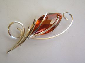 a brooch that is sitting on top of a white surface with a wire wrapped around it