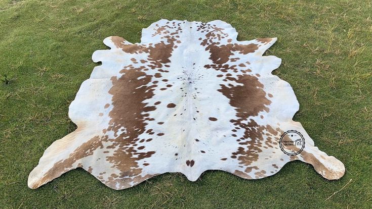 a brown and white cowhide rug on grass