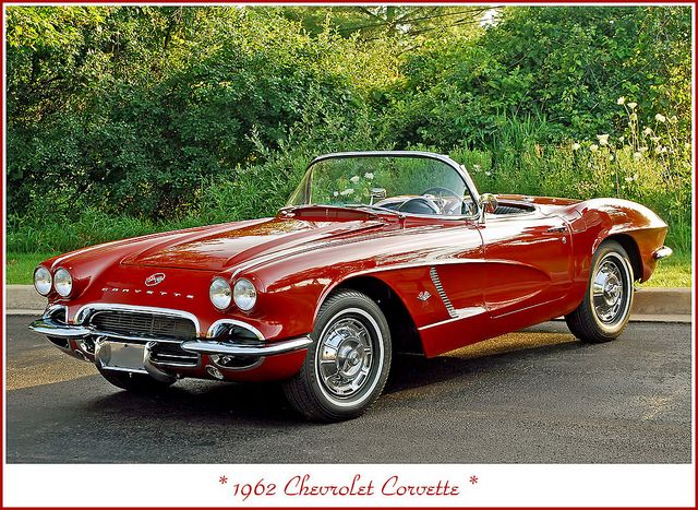 an old red convertible car parked in a parking lot