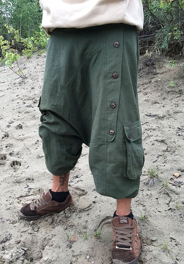 green bloomers out of heavy cotton fabric ॐ with two baggy bags and one regular pocket on the right leg. on the left leg is a raw of wooden buttons. it has an elastical waist band so it fits on perfect to your body. with the elastic bands on the ankles you can wear it as a short or 3/4 pants visually, this harem pants fits wonderfully with everything that is psychedelic, whether it's hippie, goa or psytrance parties, but also for yoga or meditation as well as in everyday life - with these comfor Green Parachute Pants For Summer Outdoor, Green Parachute Pants For Outdoor Summer, Green Baggy Harem Pants, Baggy Hippie Harem Pants With Pockets, Baggy Green Parachute Pants For Summer, Baggy Green Pants For Festival, Green Baggy Pants For Festival, Baggy Green Hippie Harem Pants, Green Baggy Harem Pants In Hippie Style