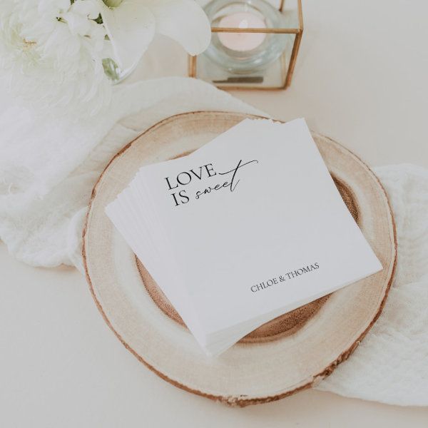 a table setting with napkins, flowers and candles on the plate that says love is sweet