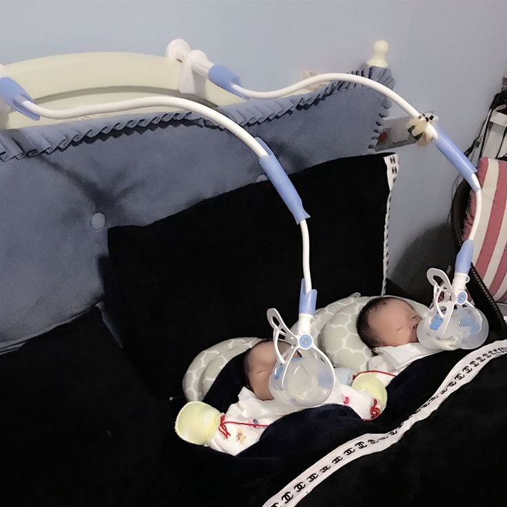 a baby laying on top of a black blanket in a crib next to a pillow