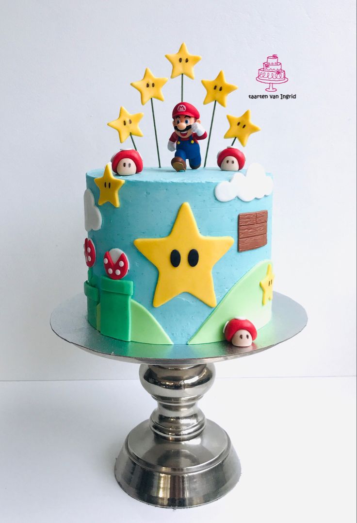 a birthday cake decorated with stars and mario bros characters on top is sitting on a silver pedestal