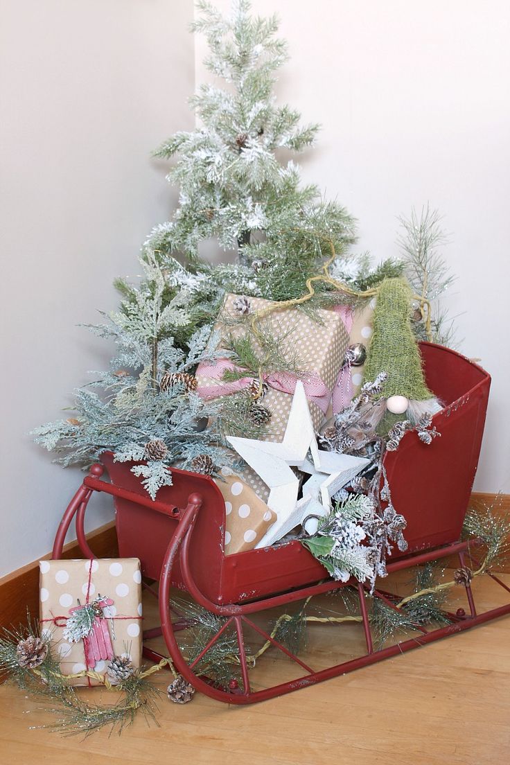 a red sleigh filled with presents under a christmas tree