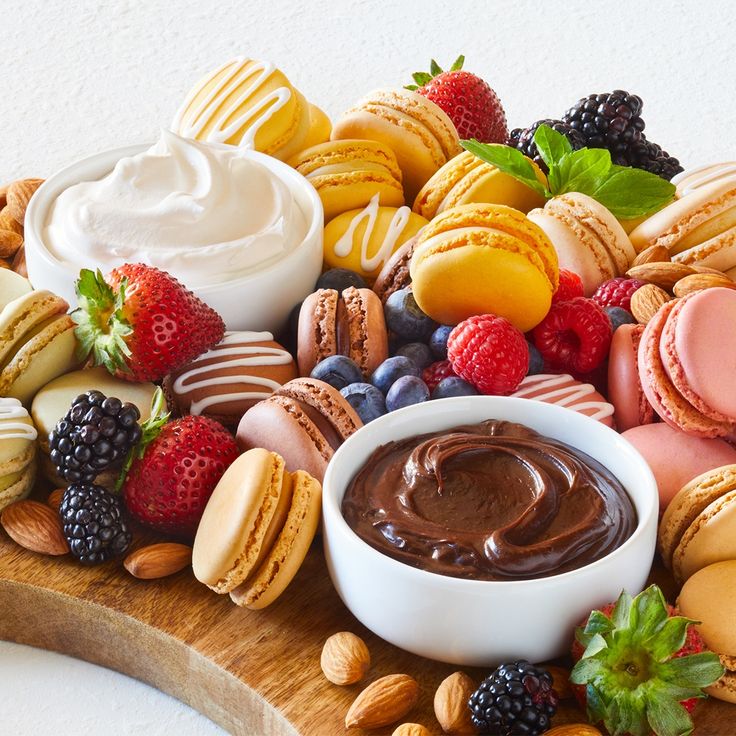 a wooden platter filled with assorted cookies, fruit and desserts on top of it