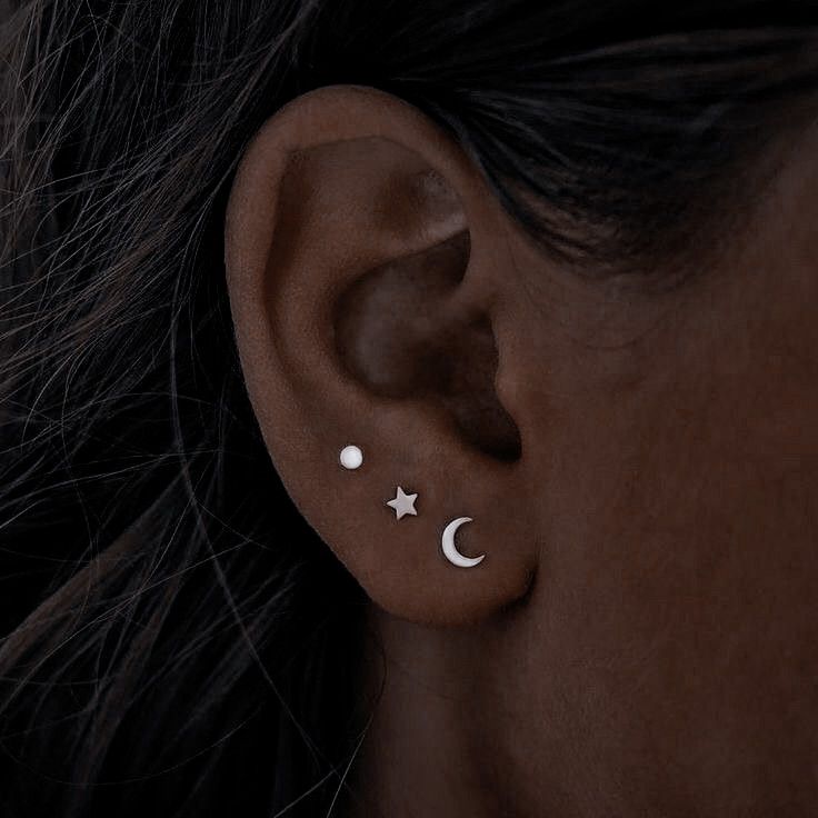 a woman's ear with two small stars and a moon on the back of it