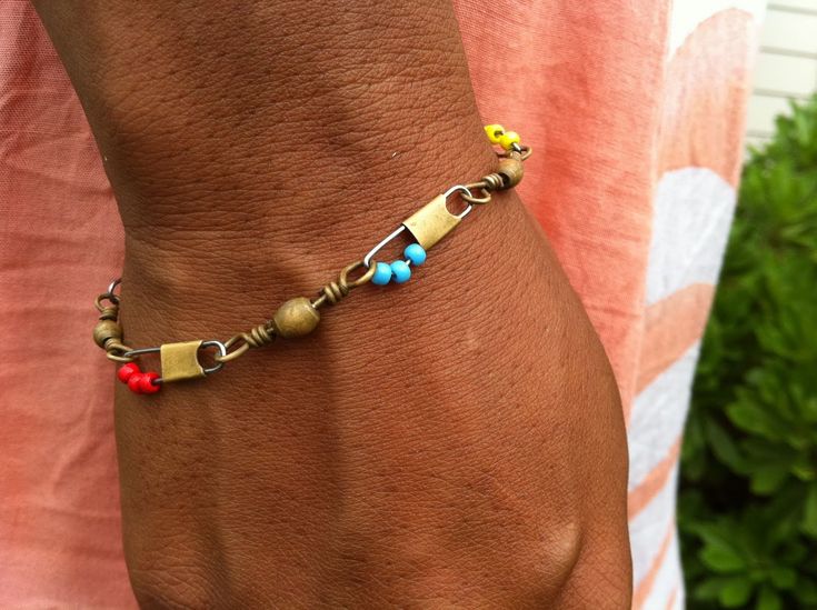 a man is wearing a bracelet with beads and charms on it's wrist while standing in front of a bush