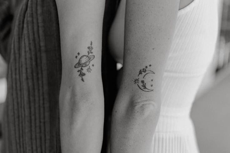 two people with matching tattoos on their arms, one holding the other's arm