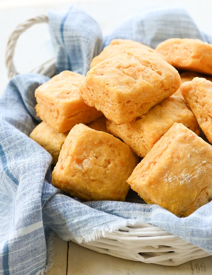 a white basket filled with small squares of bread on top of a blue and white checkered cloth