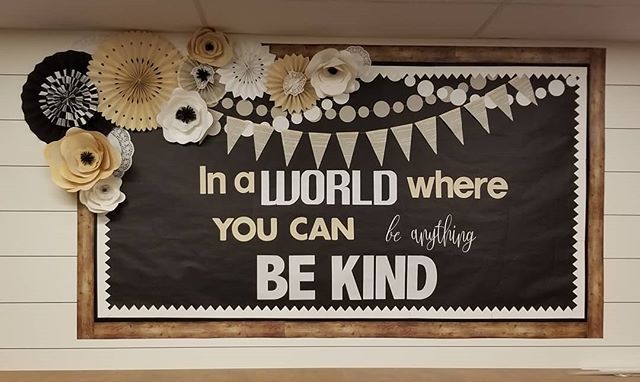 a bulletin board with paper flowers on it and a quote written in the center that says, in a world where you can be anything be kind