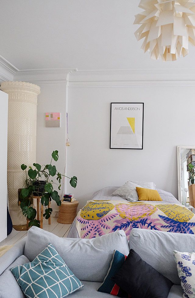 a bedroom with white walls and lots of pillows on the bed in front of it